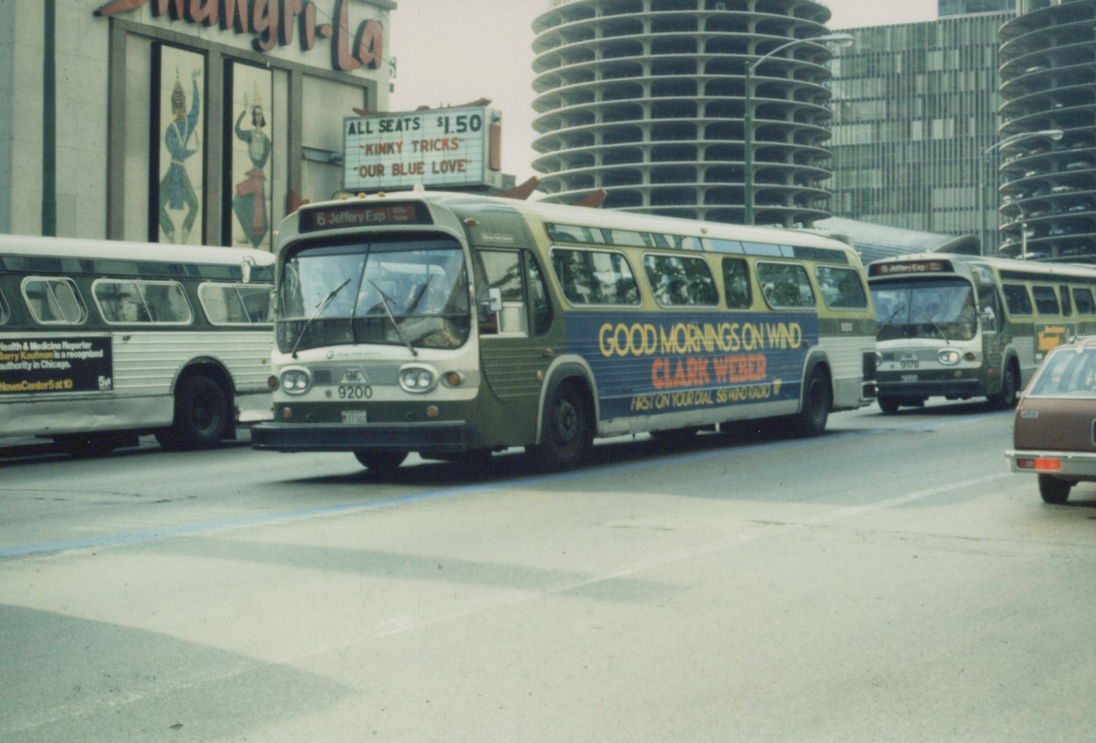 A green and cream CTA bus with route 6 Jeffery Exp is on a city street, with other buses and the Marina City towers visible in the background.
