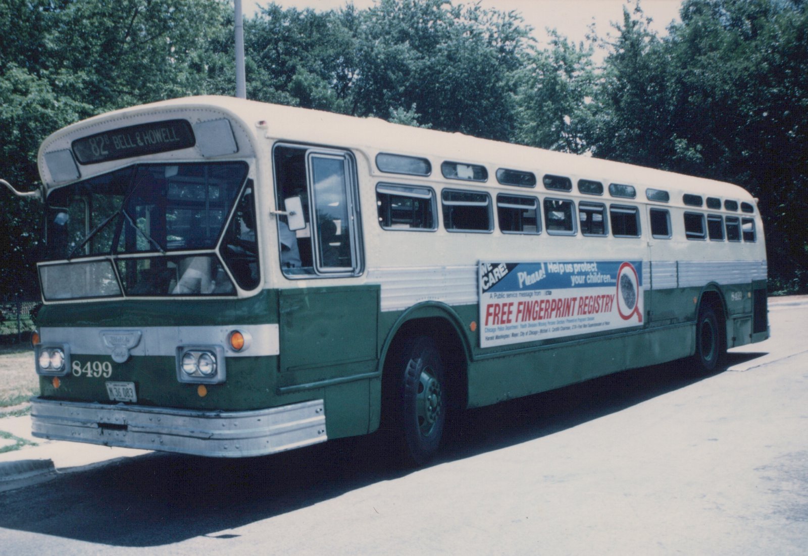 A green and cream Chicago Transit Authority bus from the 1970s is parked on a street, showing its front and side with a destination sign reading '82 Bell & Howell' and a 'Free Fingerprint Registry' advertisement.