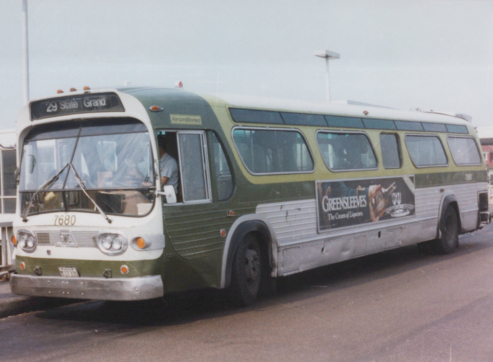 A green and cream Chicago Transit Authority bus, number 7680, is parked on a street with its driver visible and a 'Greensleeves' advertisement on its side.