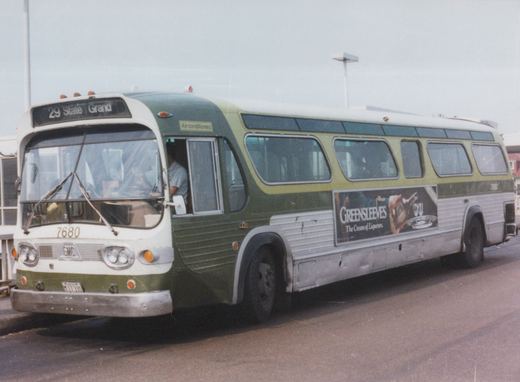 A green and cream Chicago Transit Authority bus, number 7680, is parked on a street with its driver visible and a 'Greensleeves' advertisement on its side.