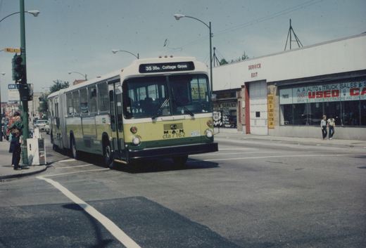 A green and cream Chicago Transit Authority bus on a city street at an intersection with a traffic light and storefronts in the background.