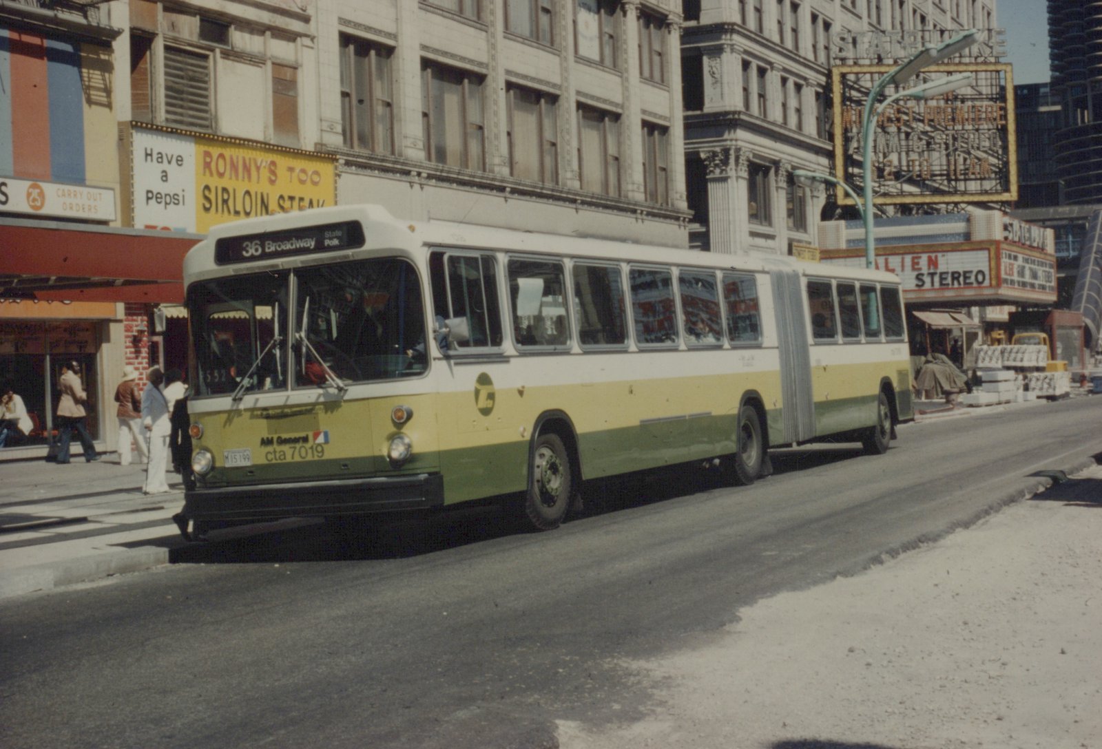 A white, yellow and green articulated CTA bus on a city street with people on the sidewalk and movie theater marquees in the background.