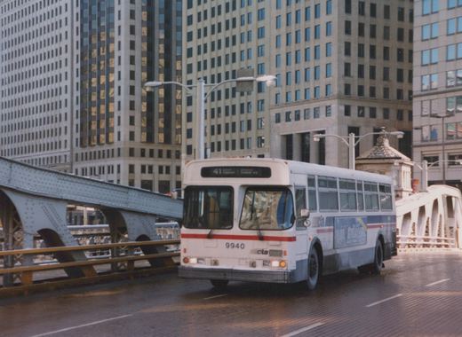 A white and red Chicago Transit Authority bus drives across a steel bridge in a city, with a route sign reading 41 and fleet number 9940 visible.