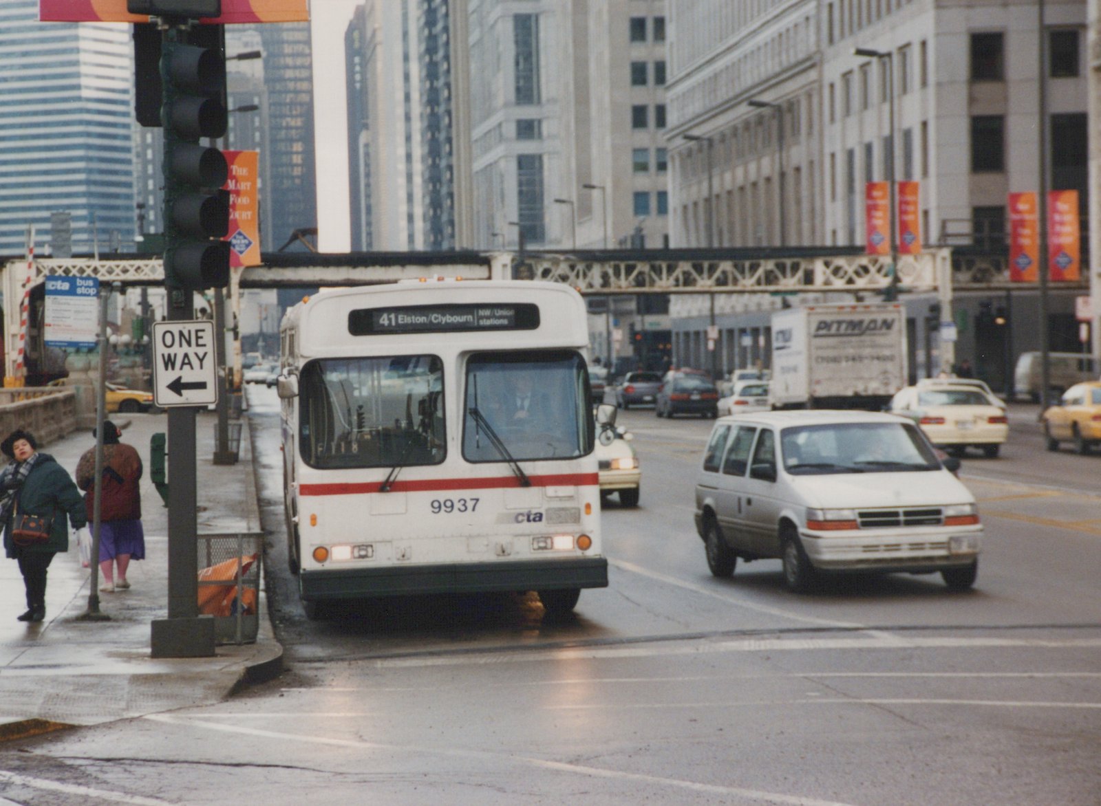 A white and red CTA bus with the number 9937 and destination sign reading 41 Elston/Clybourn is stopped on a city street. A one-way sign is visible on the sidewalk, and other cars and minivans are on the road.