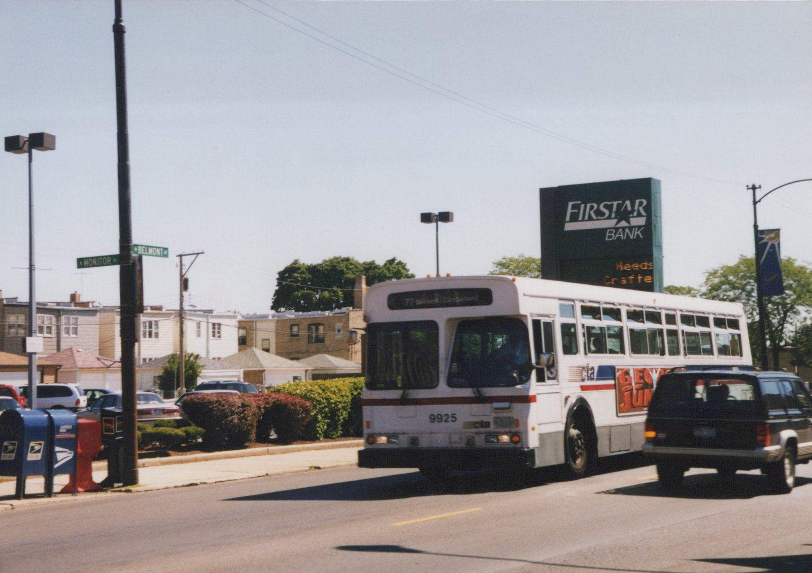 A white Chicago Transit Authority bus with the number 9925 on the front is driving down a street next to a black SUV, with street signs for Belmont and Monitor visible on a pole and a Firstar Bank billboard in the background.