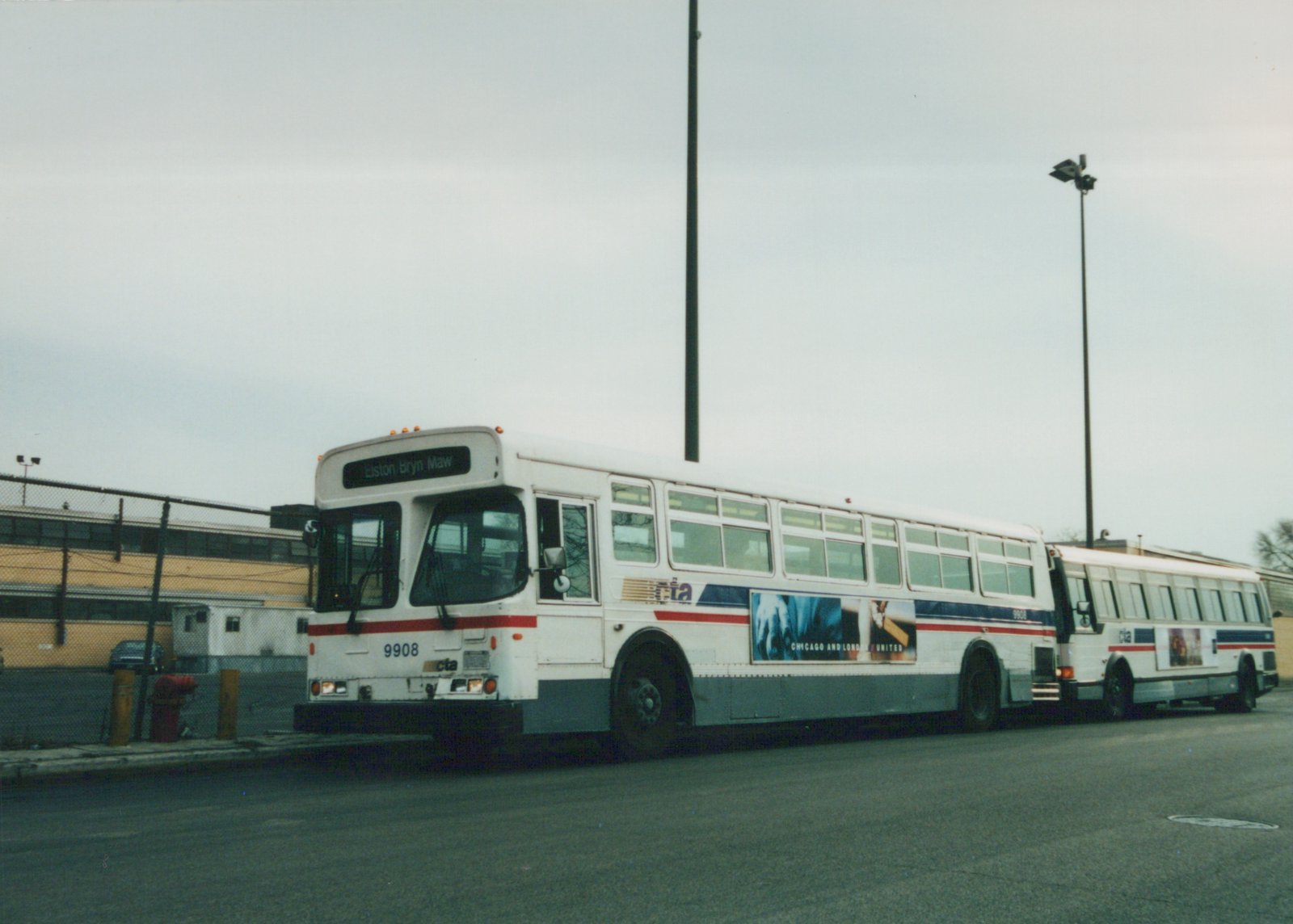 A white, blue, and red Chicago Transit Authority bus numbered 9908 is parked on a street, with a second identical bus behind it. The sky is overcast and the destination sign reads 'Elston Bryn Maw'.