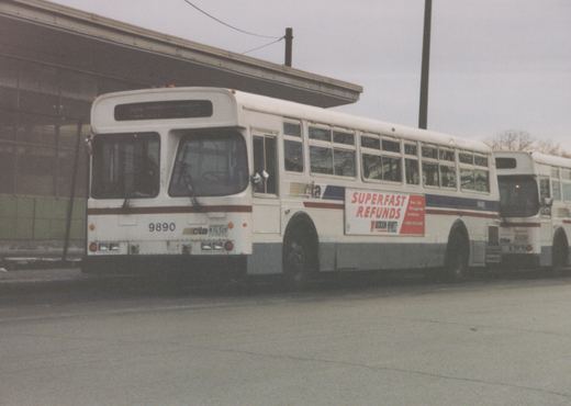 A white Chicago Transit Authority bus with the number 9890, featuring a Jackson Hewitt advertisement, parked outside a building.