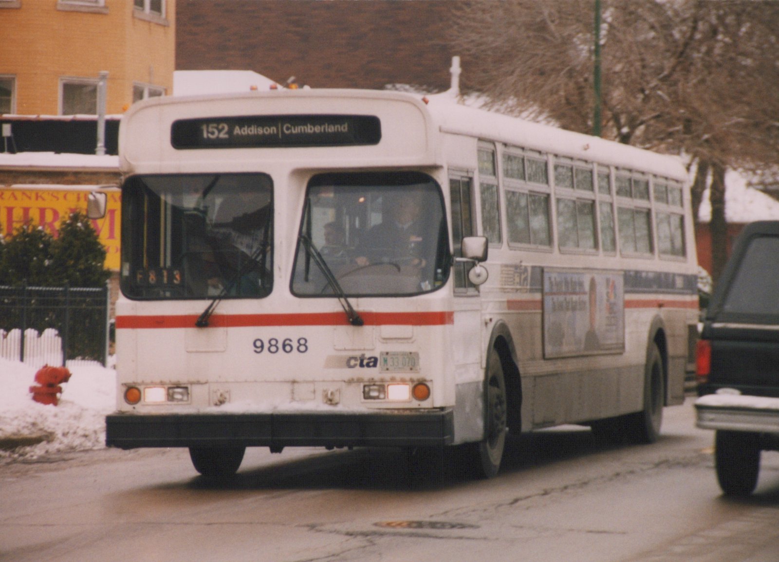 A white and red CTA bus numbered 9868 is driving on a snow-dusted city street, with a destination sign reading 152 Addison | Cumberland.
