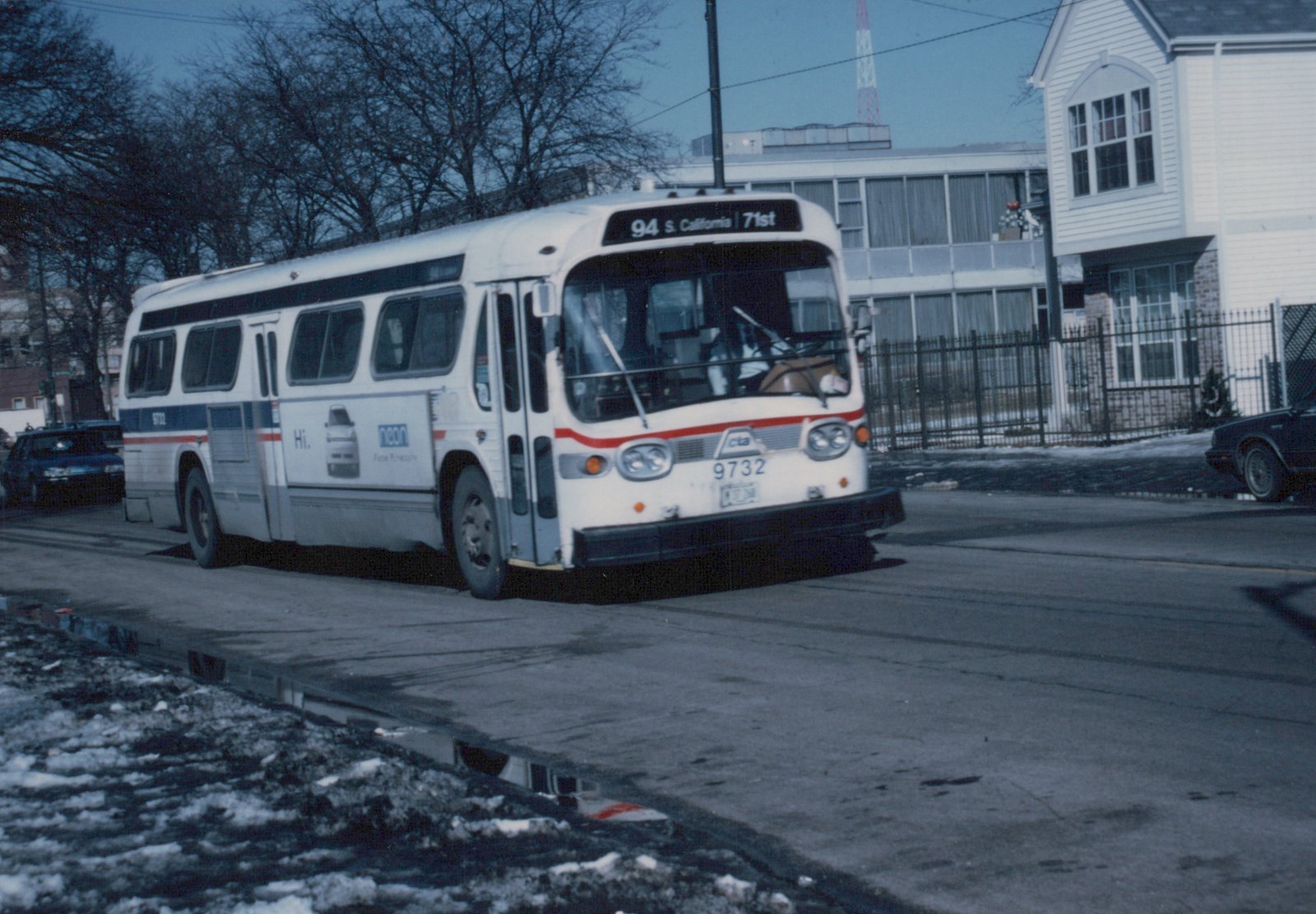 A white and blue Chicago Transit Authority bus, number 9732, is shown driving on a snowy city street with bare trees and residential buildings in the background.