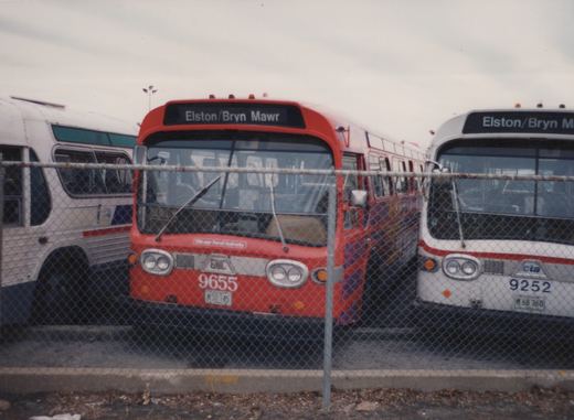 A red and a white Chicago Transit Authority bus parked side-by-side behind a chain-link fence, both displaying the destination Elston/Bryn Mawr on their front signs.