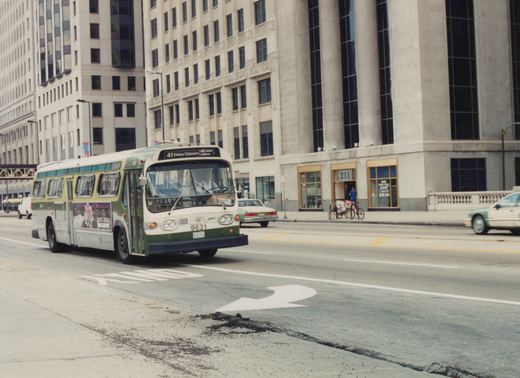 A green and white CTA bus, number 9631, drives on a city street with tall buildings in the background, heading for the 41 Elston/Clybourn route.