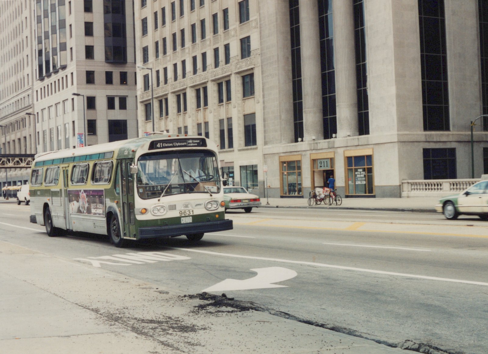 A green and white CTA bus, number 9631, drives on a city street with tall buildings in the background, heading for the 41 Elston/Clybourn route.