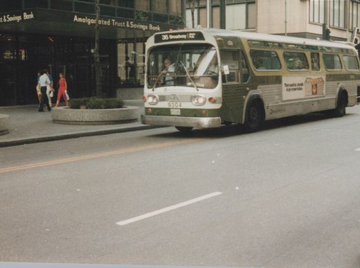 A green and white CTA bus from the 1970s, number 9304, travels down a city street with pedestrians and a bank in the background.