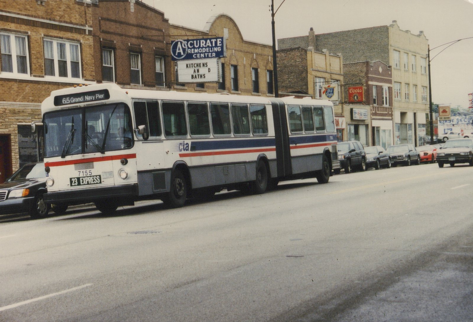 A white, blue, and red articulated CTA bus, number 7155, is driving down a city street lined with parked cars and brick buildings under an overcast sky.