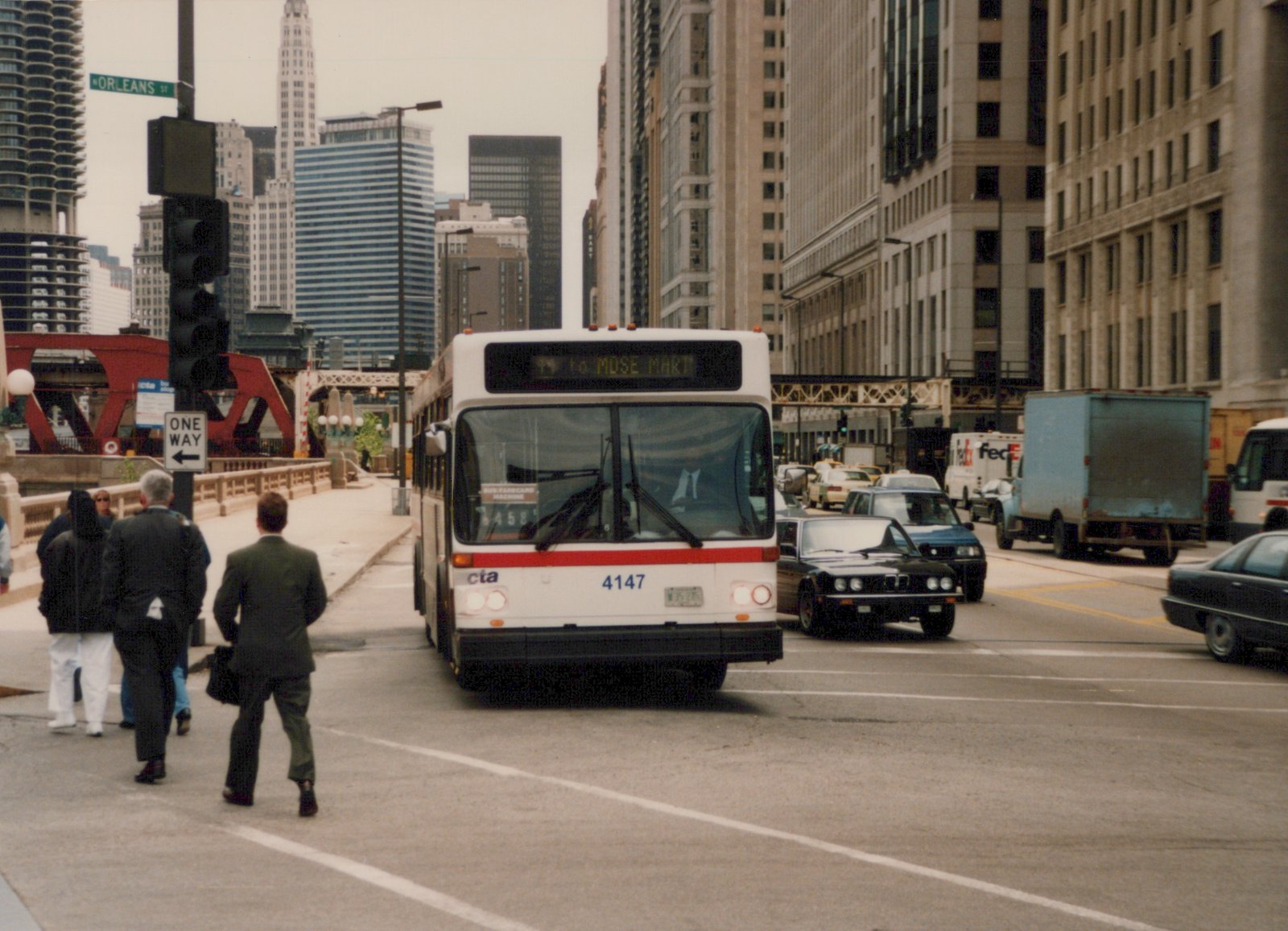 A white and red Chicago Transit Authority bus, number 4147, is on a city street with people crossing the road and tall buildings in the background.