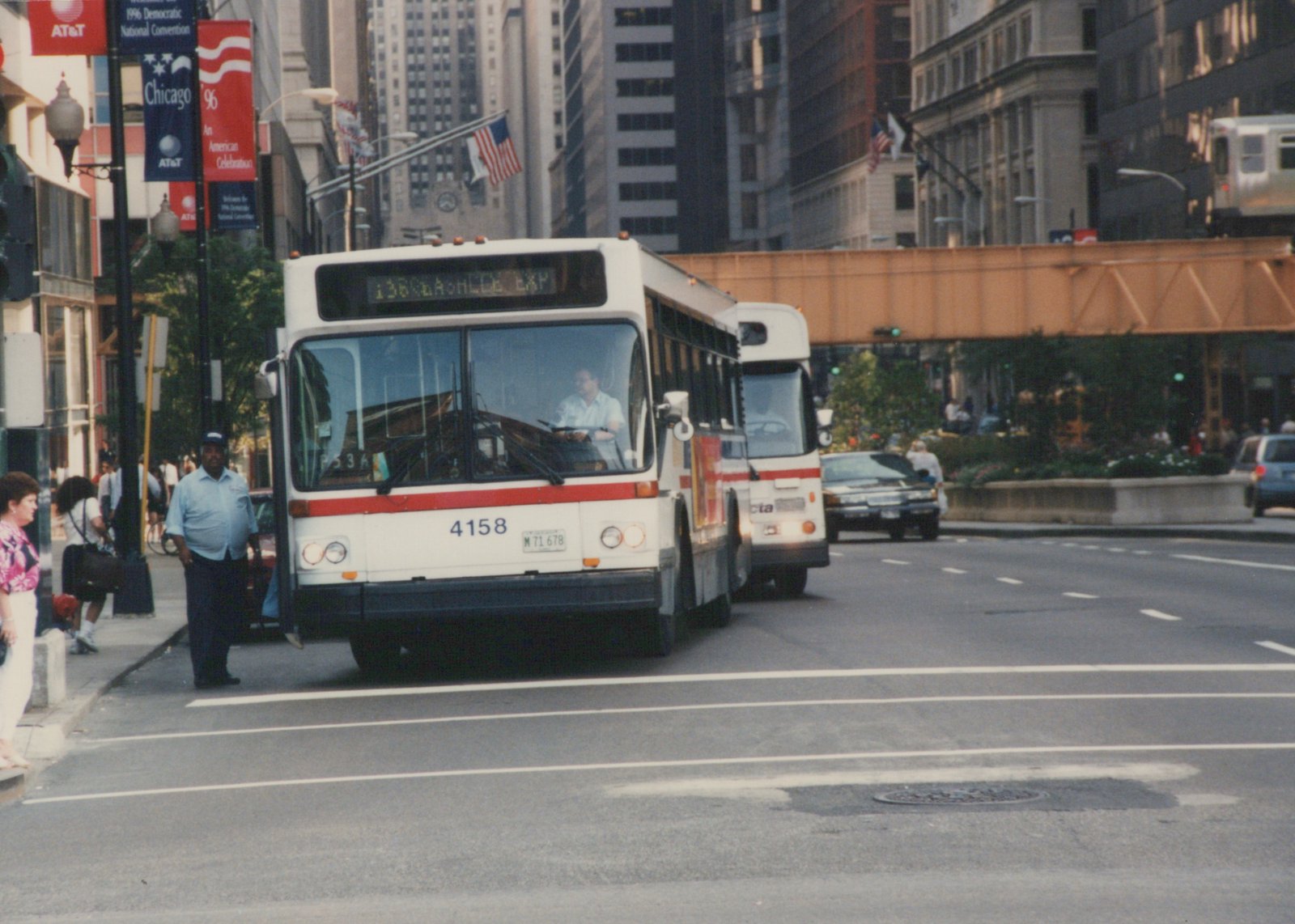 Front view of a white and red Chicago Transit Authority bus with the number 4158, stopped on a city street with pedestrians nearby and a second bus following.