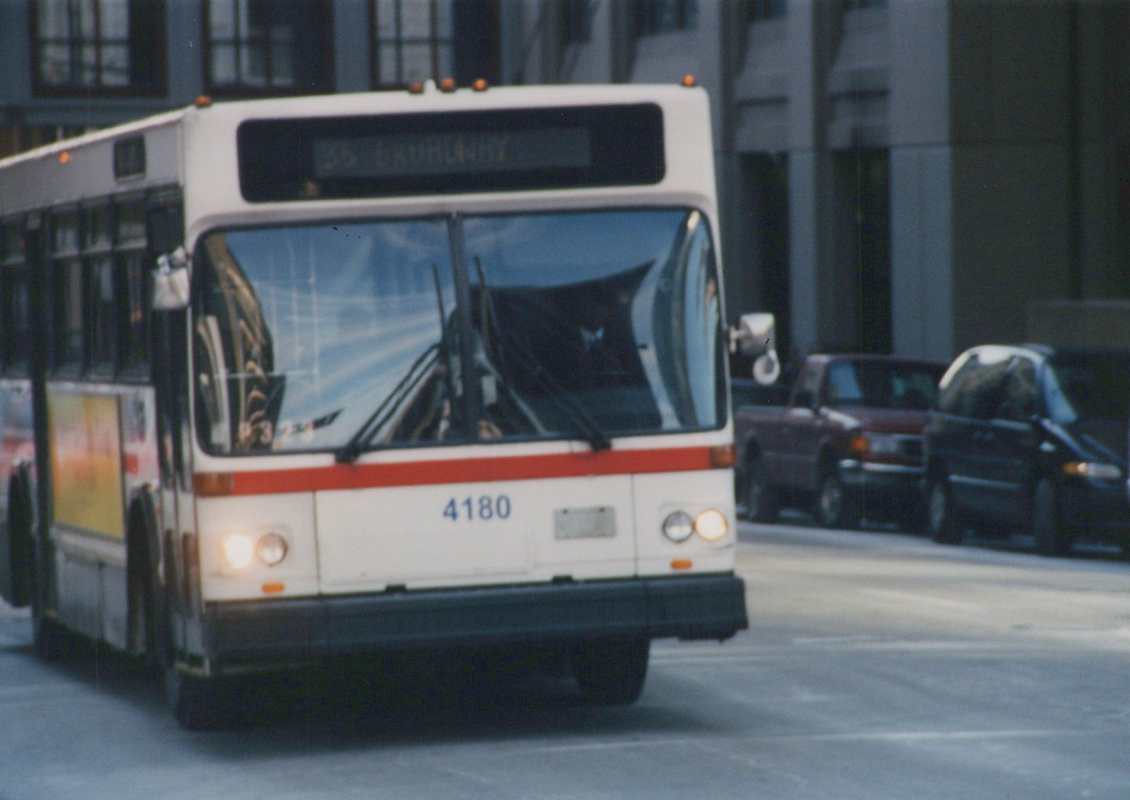 A white and red Chicago Transit Authority bus with number 4180 on its front, displaying route 36 Broadway, driving down a city street with other vehicles in the background.