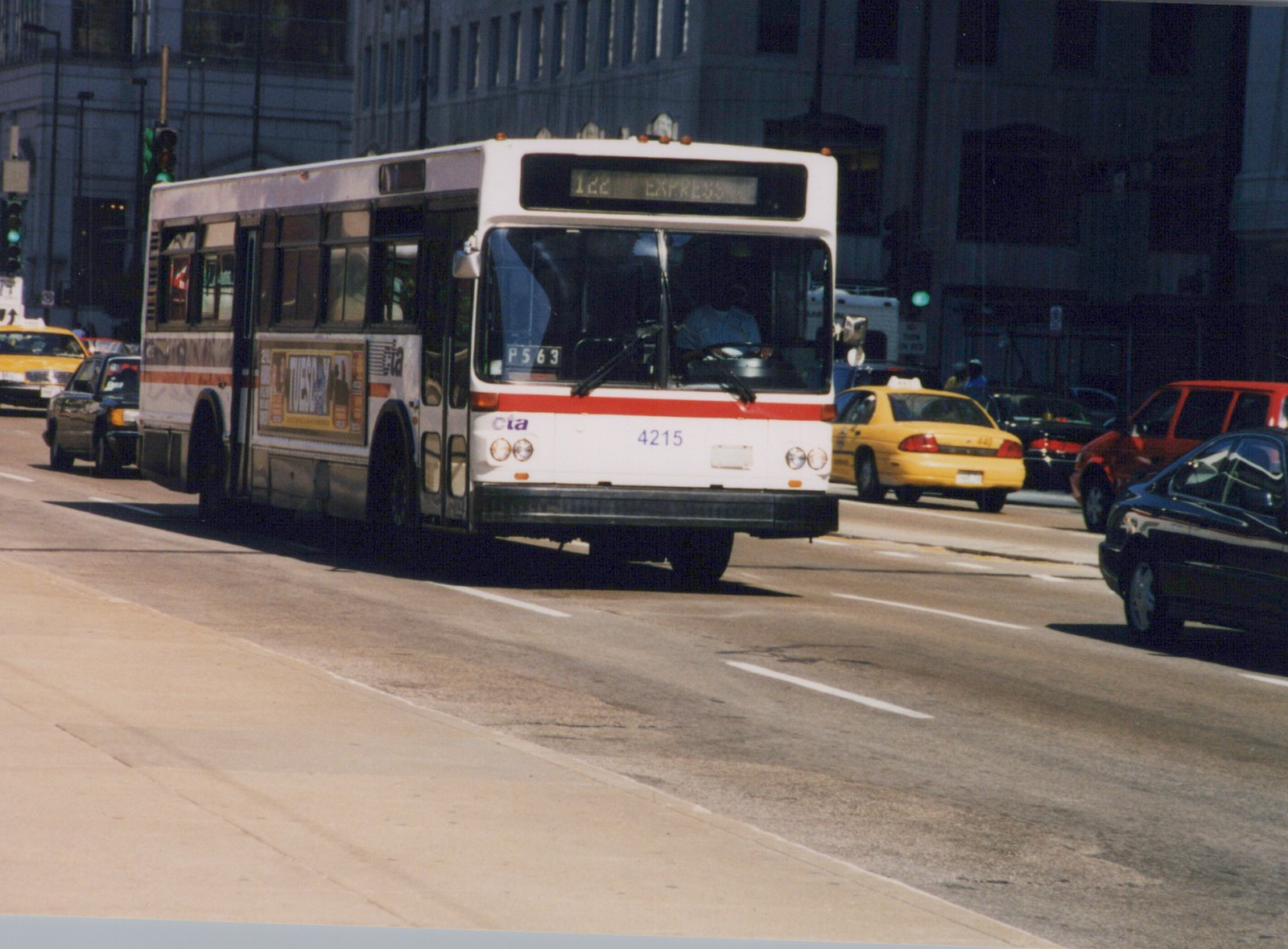 A white and red Chicago Transit Authority motor bus, number 4215, is driving down a city street with other cars around it.