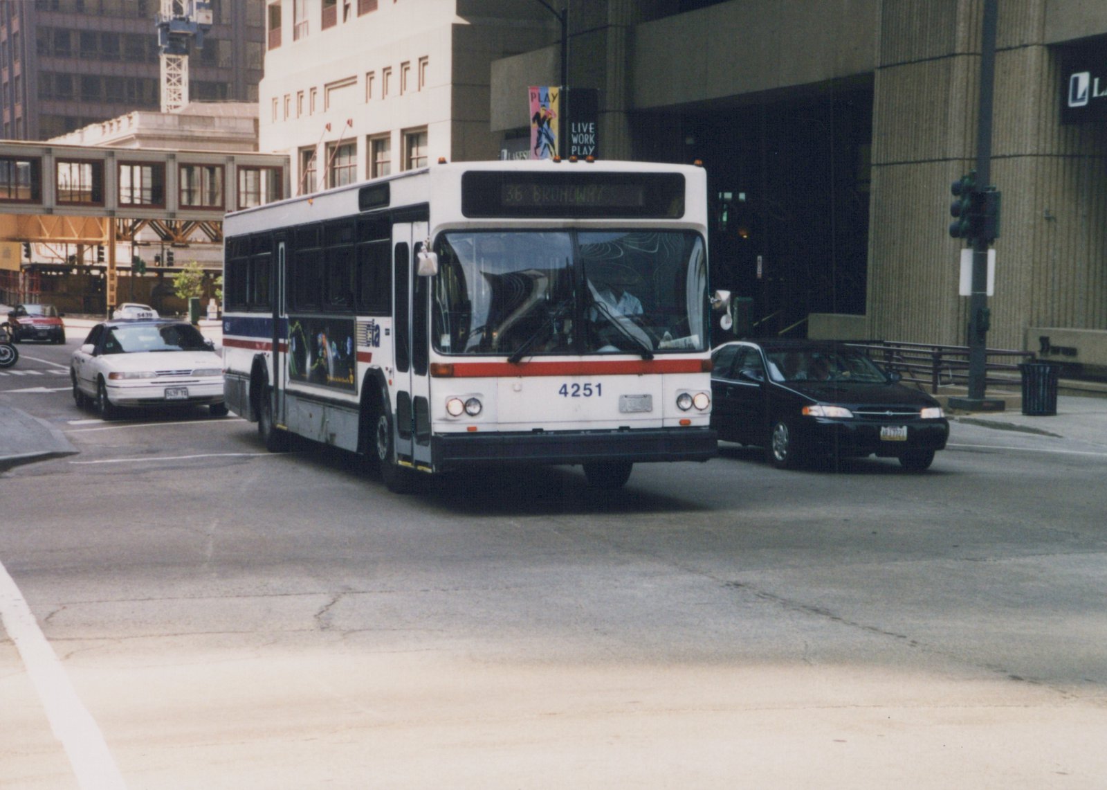 A white CTA bus with the number 4251 and route 36 Broadway sign is turning on a city street, surrounded by cars and tall buildings.