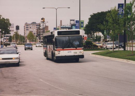 A white and red Chicago Transit Authority bus with the number 4270 on the front is driving down a city street with other cars and trees visible.