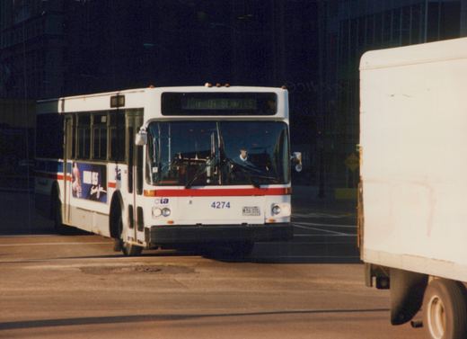 A white and red Chicago Transit Authority bus, number 4274, is parked on a street with a driver visible inside and a yellow 'SLOW' sign in the background.
