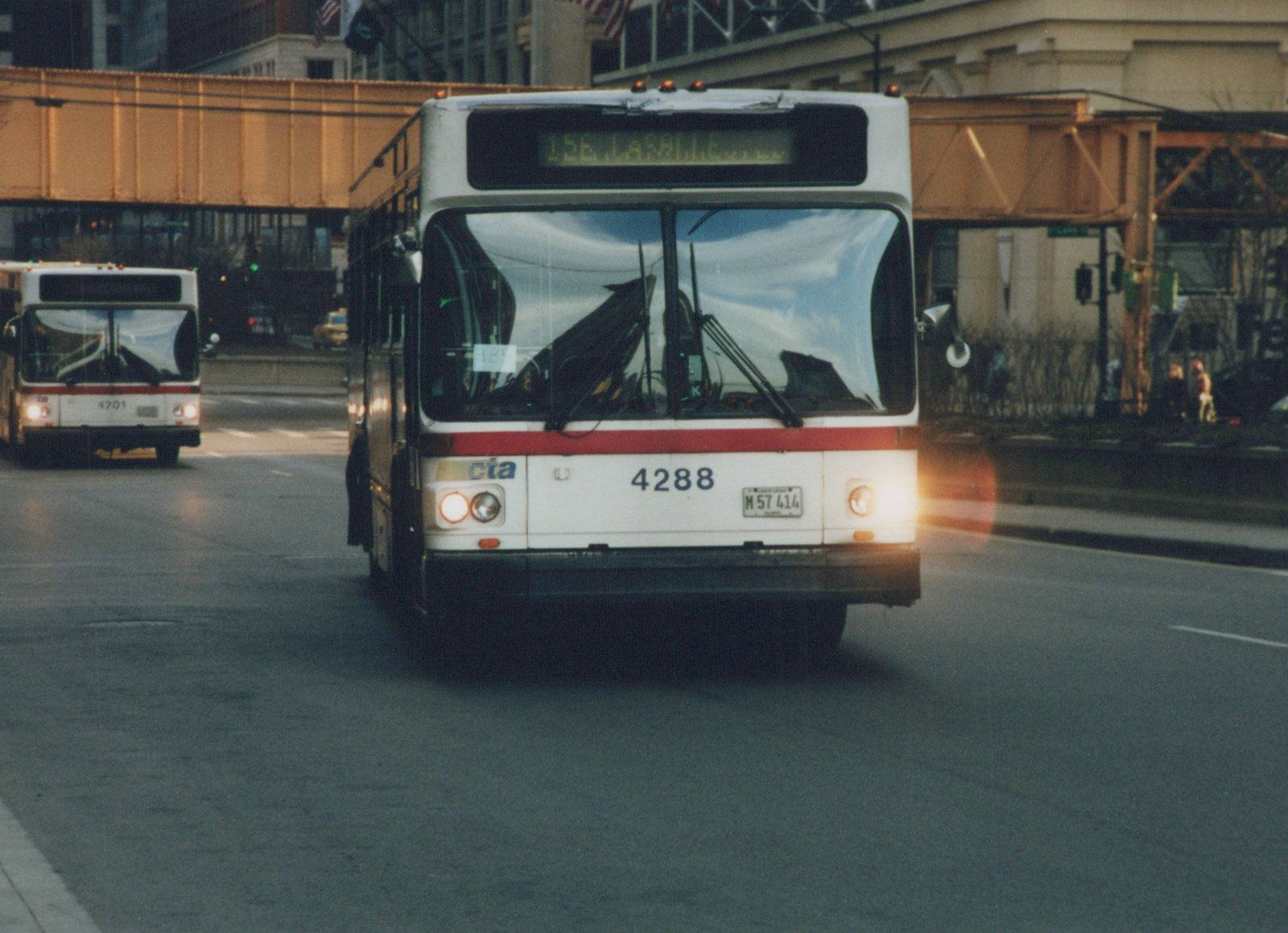 Front view of a white CTA bus with fleet number 4288 and destination sign reading '156 LA SALLE...' on a city street, with another CTA bus and an elevated train line in the background.