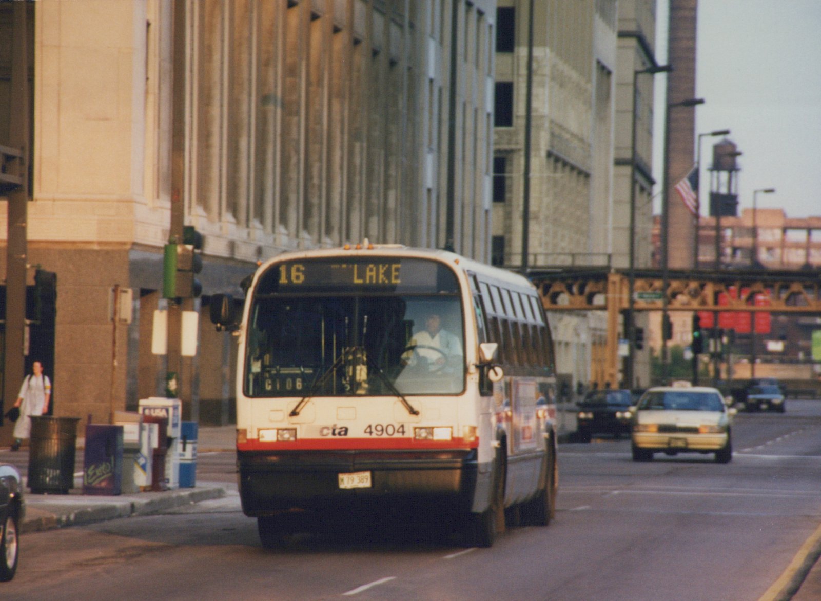 A white and red Chicago Transit Authority bus, number 4904, is driving down a city street with an elevated railway in the background.