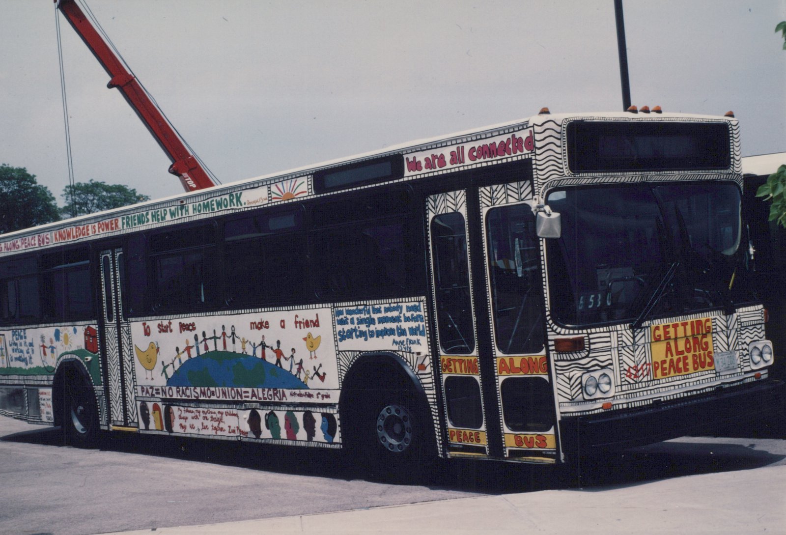 A white Chicago Transit Authority bus with colorful peace-themed artwork is parked on a city street on a sunny day; the bus number 4217 is visible.