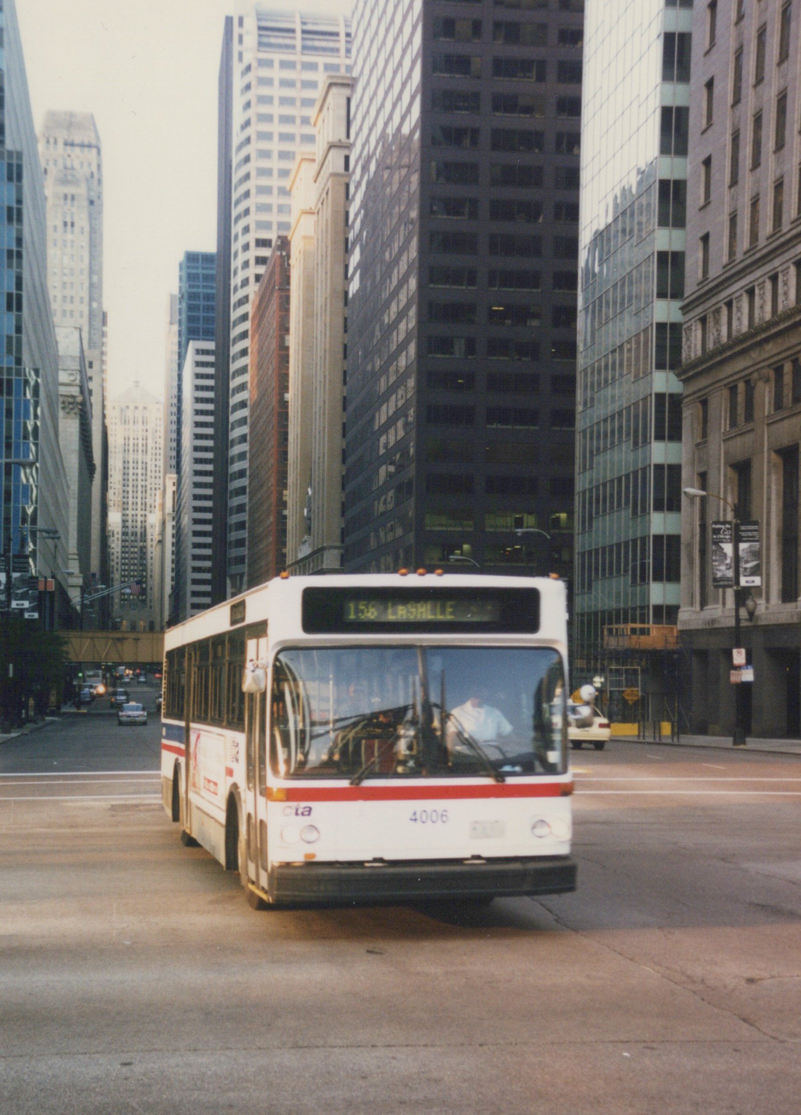 A white Chicago Transit Authority bus with the number 4006 and route 156 LaSALLE on its sign is driving down a city street lined with tall buildings.