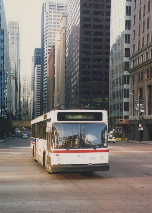 A white Chicago Transit Authority bus with the number 4006 and route 156 LaSALLE on its sign is driving down a city street lined with tall buildings.