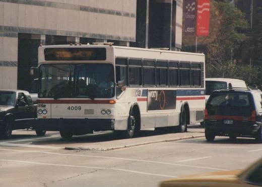A white CTA bus with the number 4009 is driving down a city street, surrounded by other vehicles, with a large 'Chicago '96' banner visible on a building in the background.