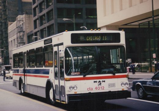 A white and blue Chicago Transit Authority bus with the number 4012 on its front bumper is driving on a city street with tall buildings in the background.
