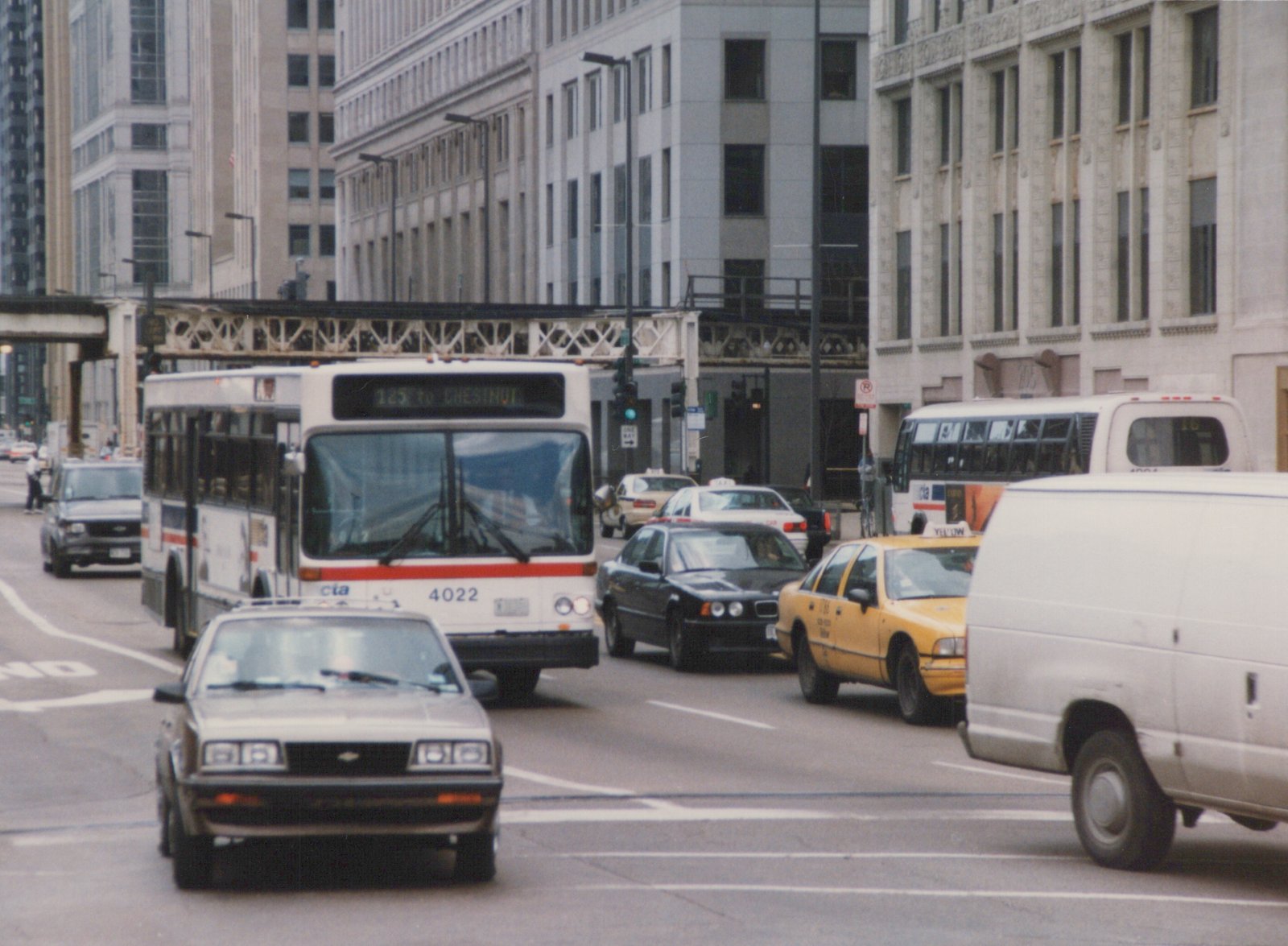 A white Chicago Transit Authority bus, number 4022, on a city street with other vehicles and an elevated structure overhead.
