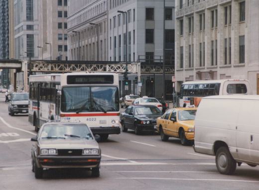 A white Chicago Transit Authority bus, number 4022, on a city street with other vehicles and an elevated structure overhead.