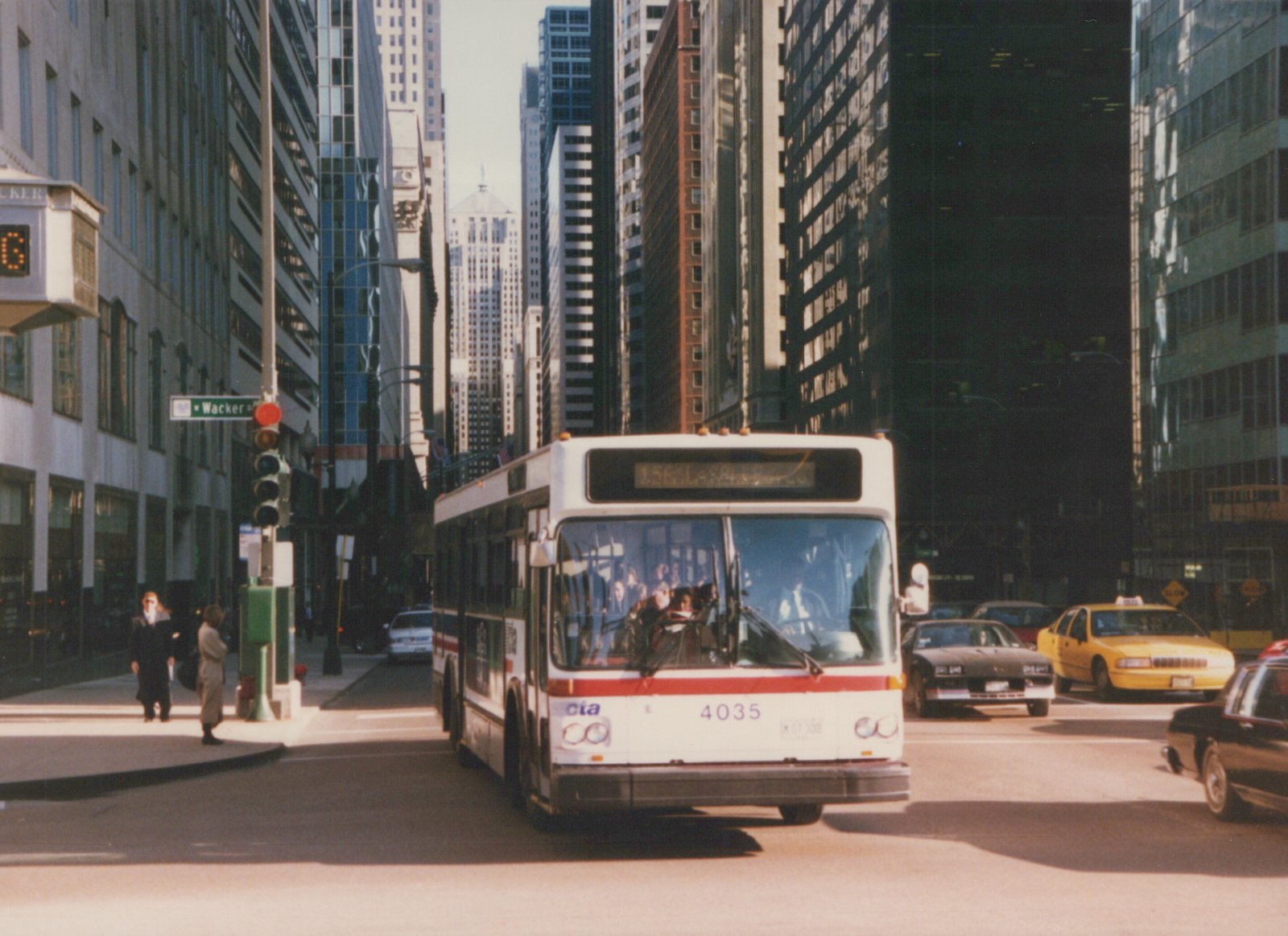 A white and red Chicago Transit Authority bus, number 4035, is stopped at an intersection on Wacker Drive, surrounded by tall buildings and other cars.