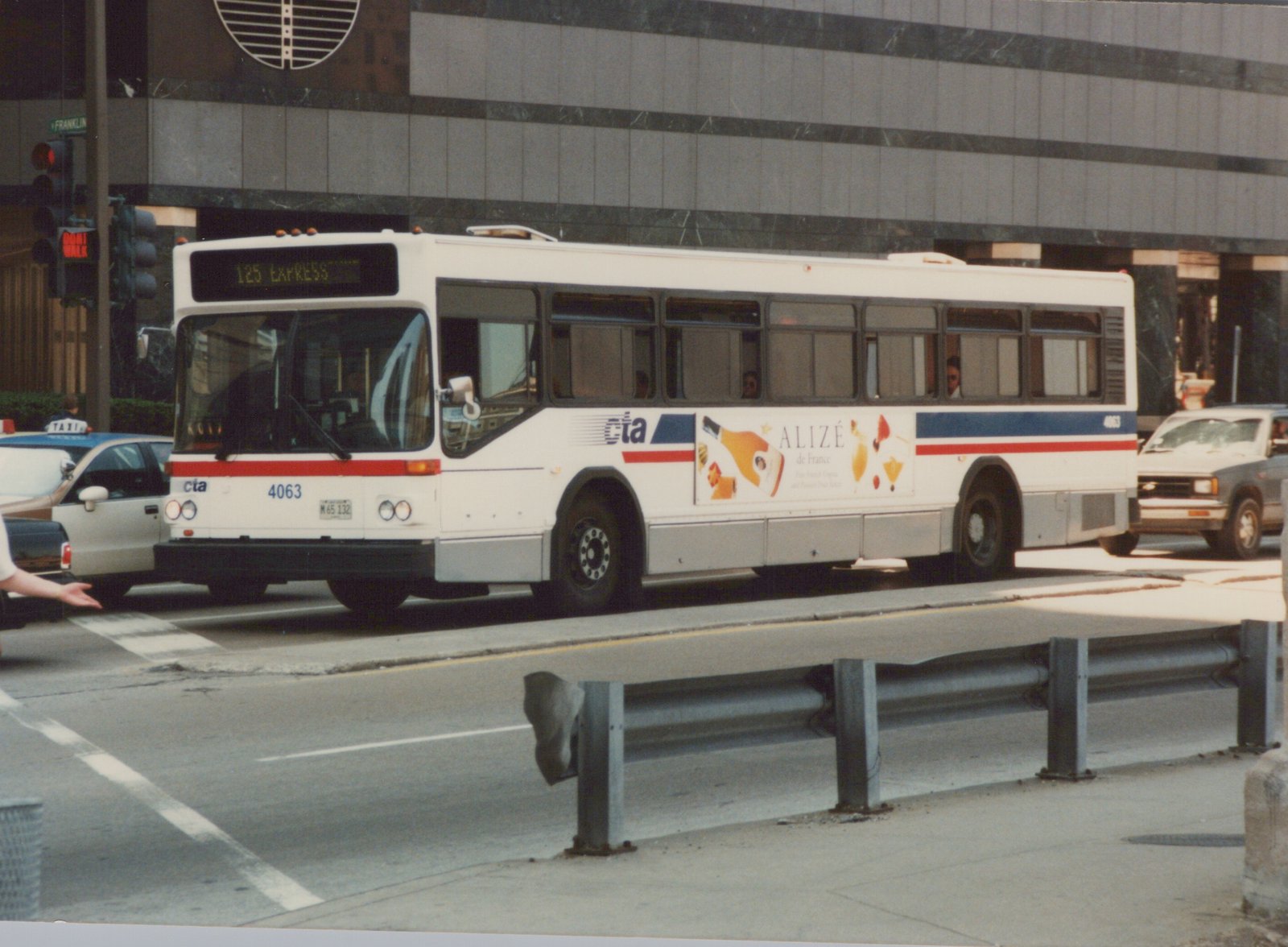 A white and blue Chicago Transit Authority bus, number 4063, labeled 125 Express, is on a city street with a taxi and truck nearby, under a clear sky in summer.