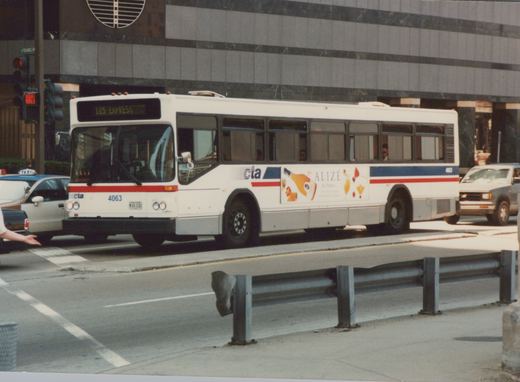 A white and blue Chicago Transit Authority bus, number 4063, labeled 125 Express, is on a city street with a taxi and truck nearby, under a clear sky in summer.