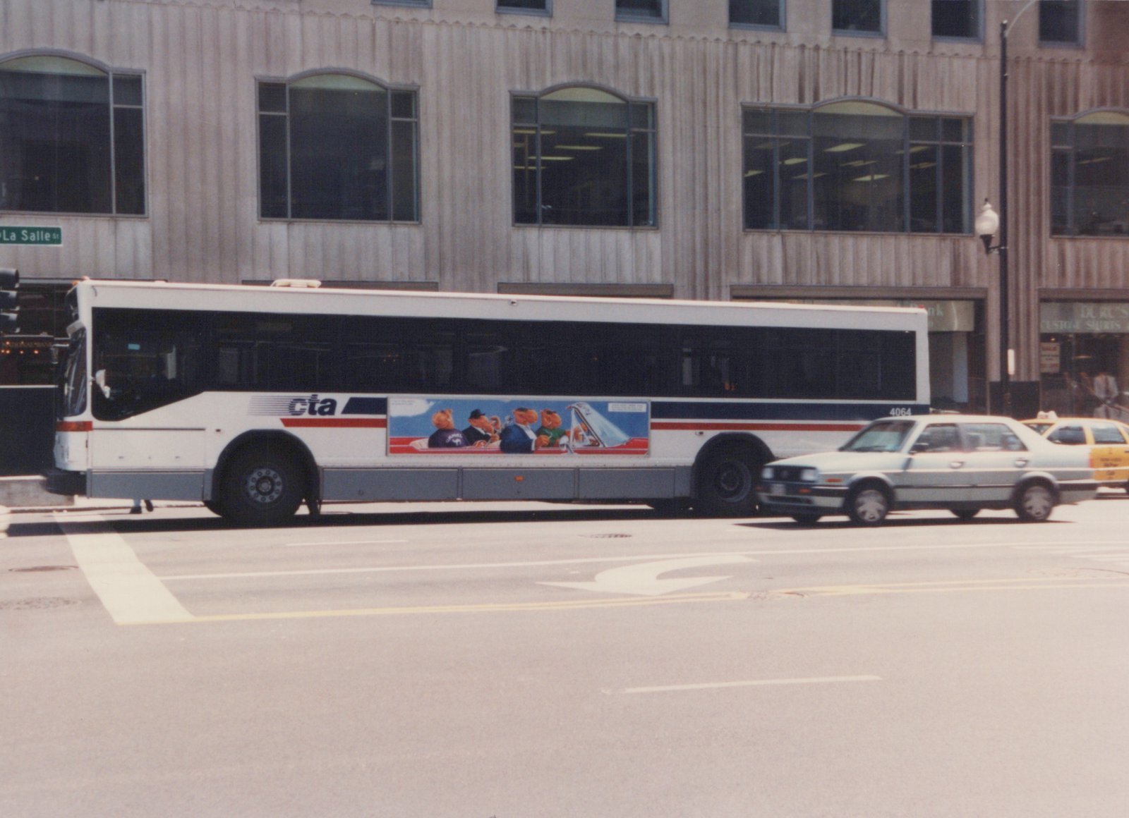 Side view of a white CTA motor bus, number 4064, stopped on a city street with a building and passing cars in the background.