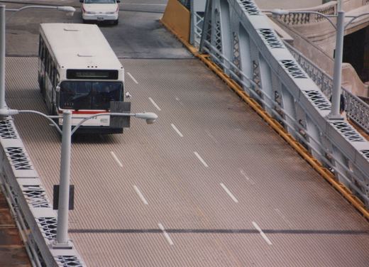 A white Pace bus with the number 4093 and a destination sign reading '44 KH LINE' is driving on the Franklin Street Bridge, with a white car following behind. The bridge has metal railings and a textured road surface.