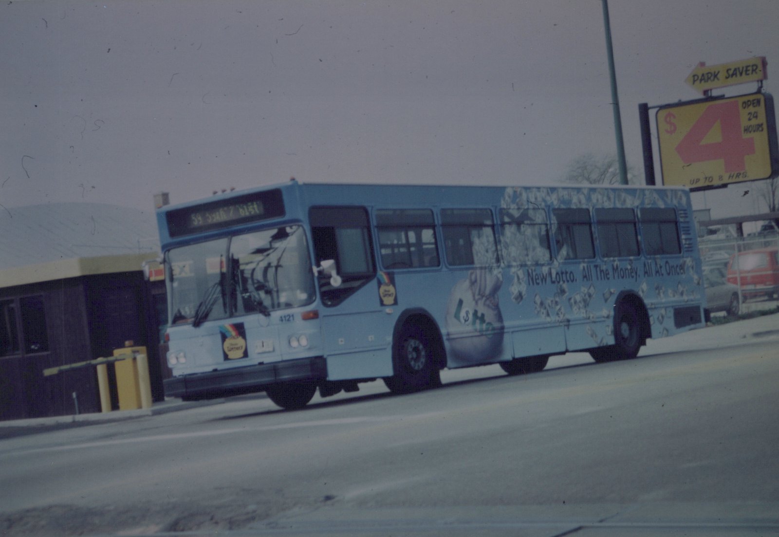 A Chicago Transit Authority motor bus, number 4121, with a New Lotto advertisement on its side, is driving down a street on a cloudy day.