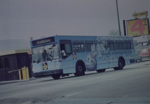 A Chicago Transit Authority motor bus, number 4121, with a New Lotto advertisement on its side, is driving down a street on a cloudy day.