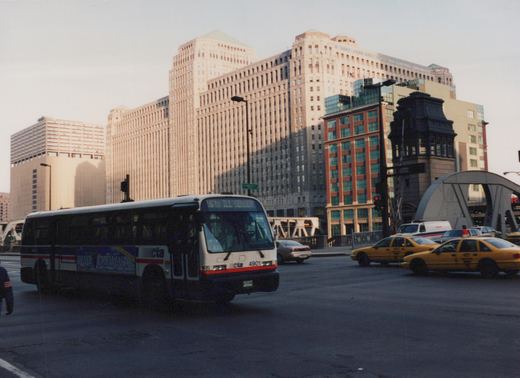 A white and red Chicago Transit Authority bus with the number 4901 is turning on a city street, with tall buildings, yellow taxis, and a street sign for South LaSalle Street visible in the background.