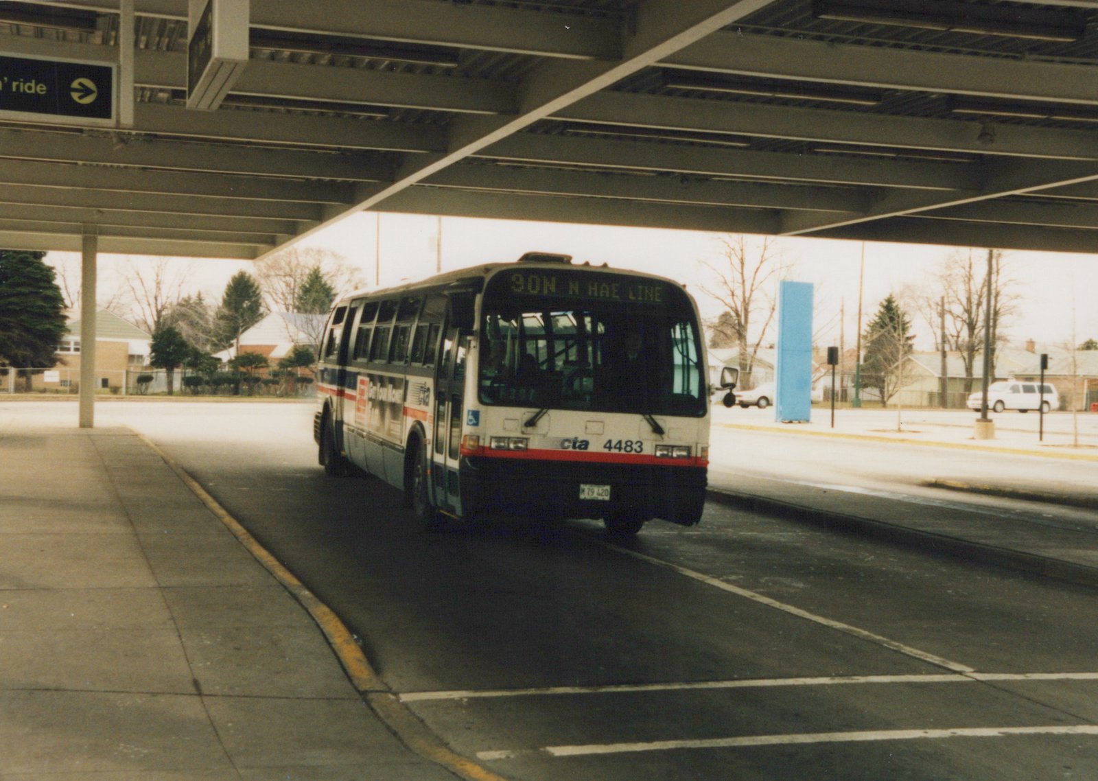 A white and blue CTA bus, number 4483, with the destination '90N N HAE LINE' on its sign, is parked under a concrete overpass on a winter day.