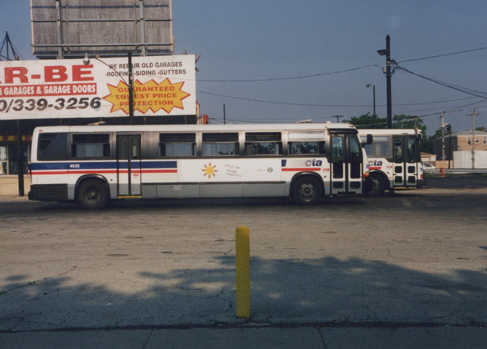 Two white CTA buses with blue and red stripes are parked on a street; the lead bus has the number 4626 and a Starbucks Frappuccino ad on its side.