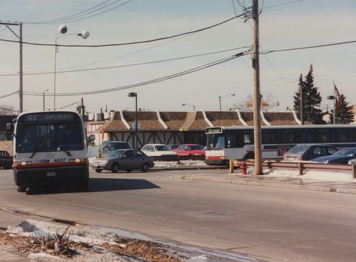 A white and red CTA bus with the number 4637 and destination '62 Archer' is driving down a street with snow on the ground and other cars around it.