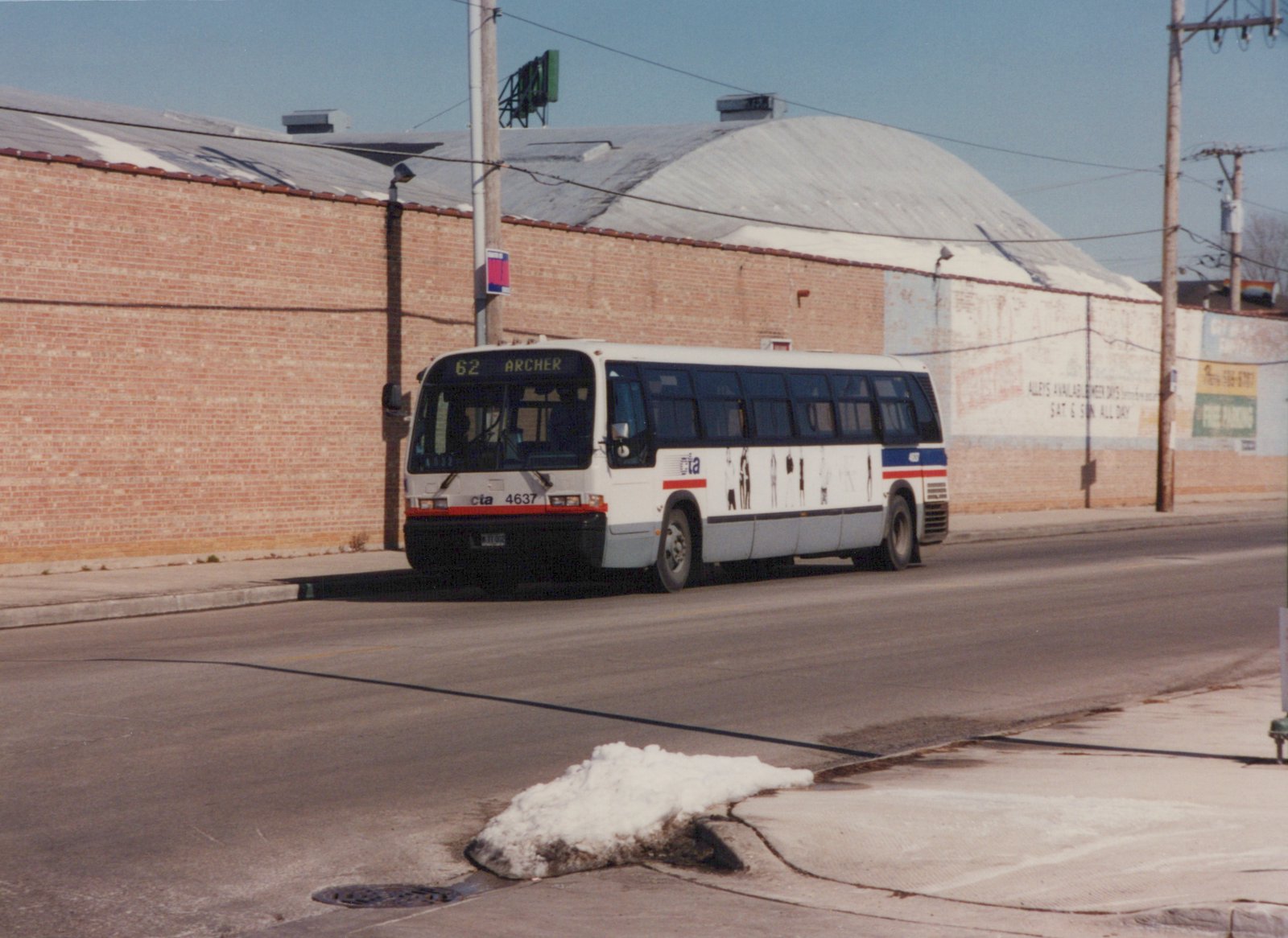 A white Chicago Transit Authority bus with red and blue stripes, numbered 4637, is shown on a city street with melting snow on the curb and a brick building in the background.