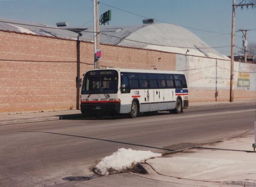 A white Chicago Transit Authority bus with red and blue stripes, numbered 4637, is shown on a city street with melting snow on the curb and a brick building in the background.