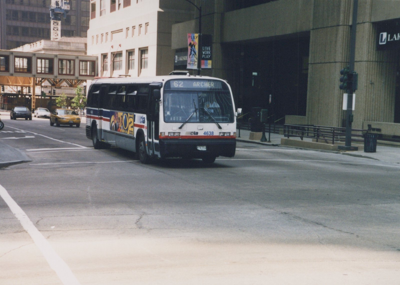 A white, red, and blue Chicago Transit Authority bus, number 4638, is driving on a city street with a yellow taxi and other cars in the background. The bus's destination sign reads '62 ARCHER'.