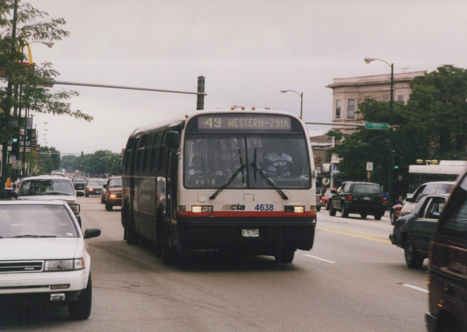 A white and red Chicago Transit Authority bus, number 4638, on route 49 Western-79th, driving down a busy street with other cars and a green street sign for Lawrence Ave visible.