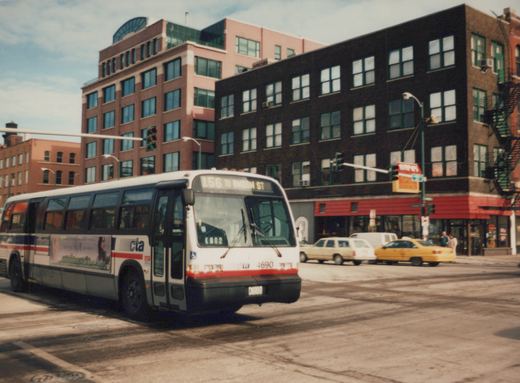 A white, red, and blue CTA bus, number 4690, is turning on a city street with tall buildings in the background.